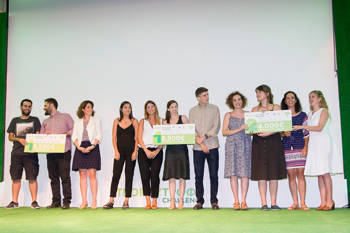 Three groups of young people stand on stage holding their trophy and smiling for a commemorative photo